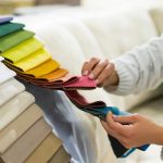 the-woman-chooses-the-fabric-on-the-sofa-textile-industry-background